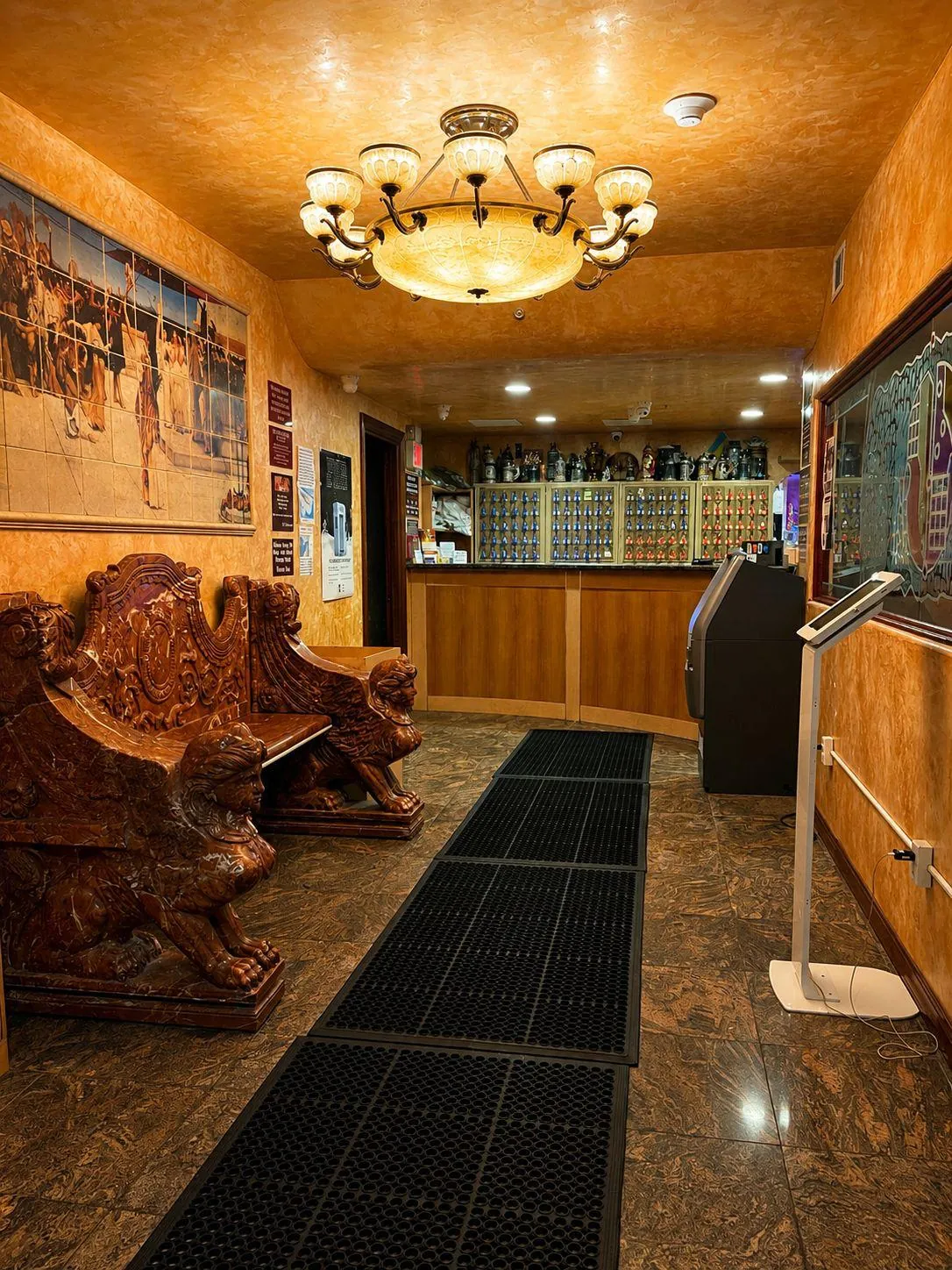The front desk at the end of the lobby, carved wooden lion benches either side.