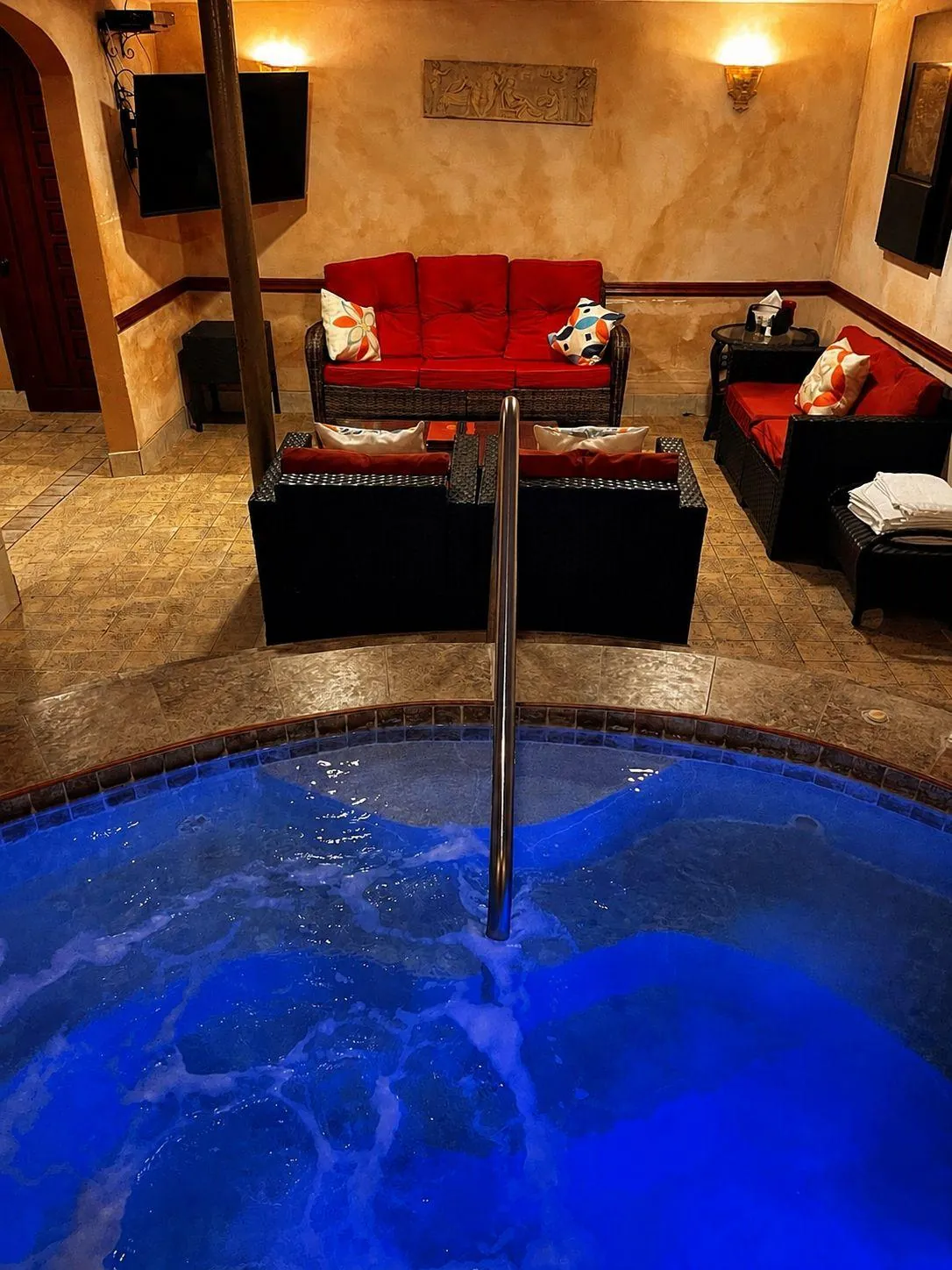 The VIP room's own jacuzzi, lit blue, with the red sofas beyond it.