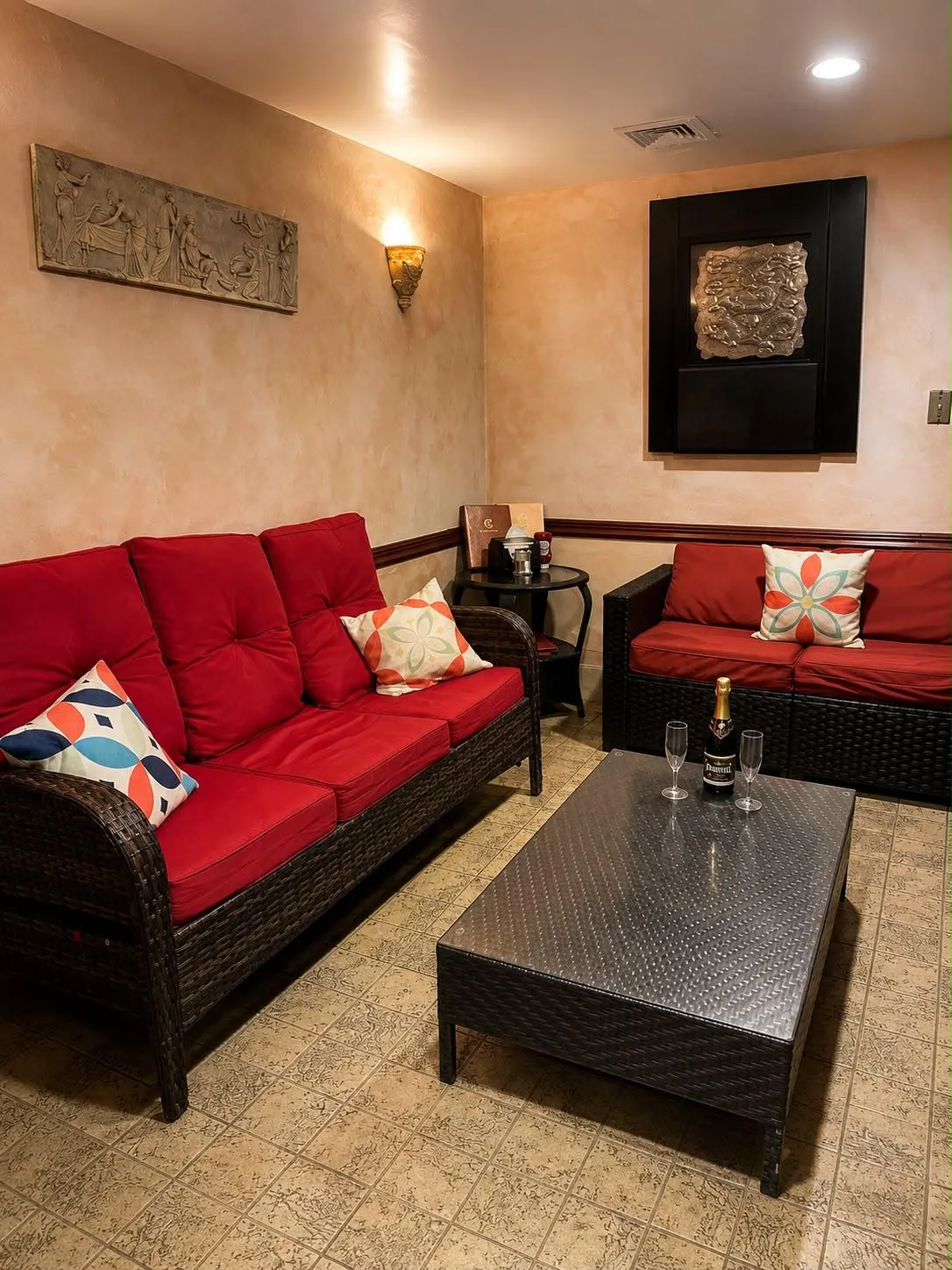 The VIP private room: red sofas, a low table with a bottle and glasses, warm plaster walls.
