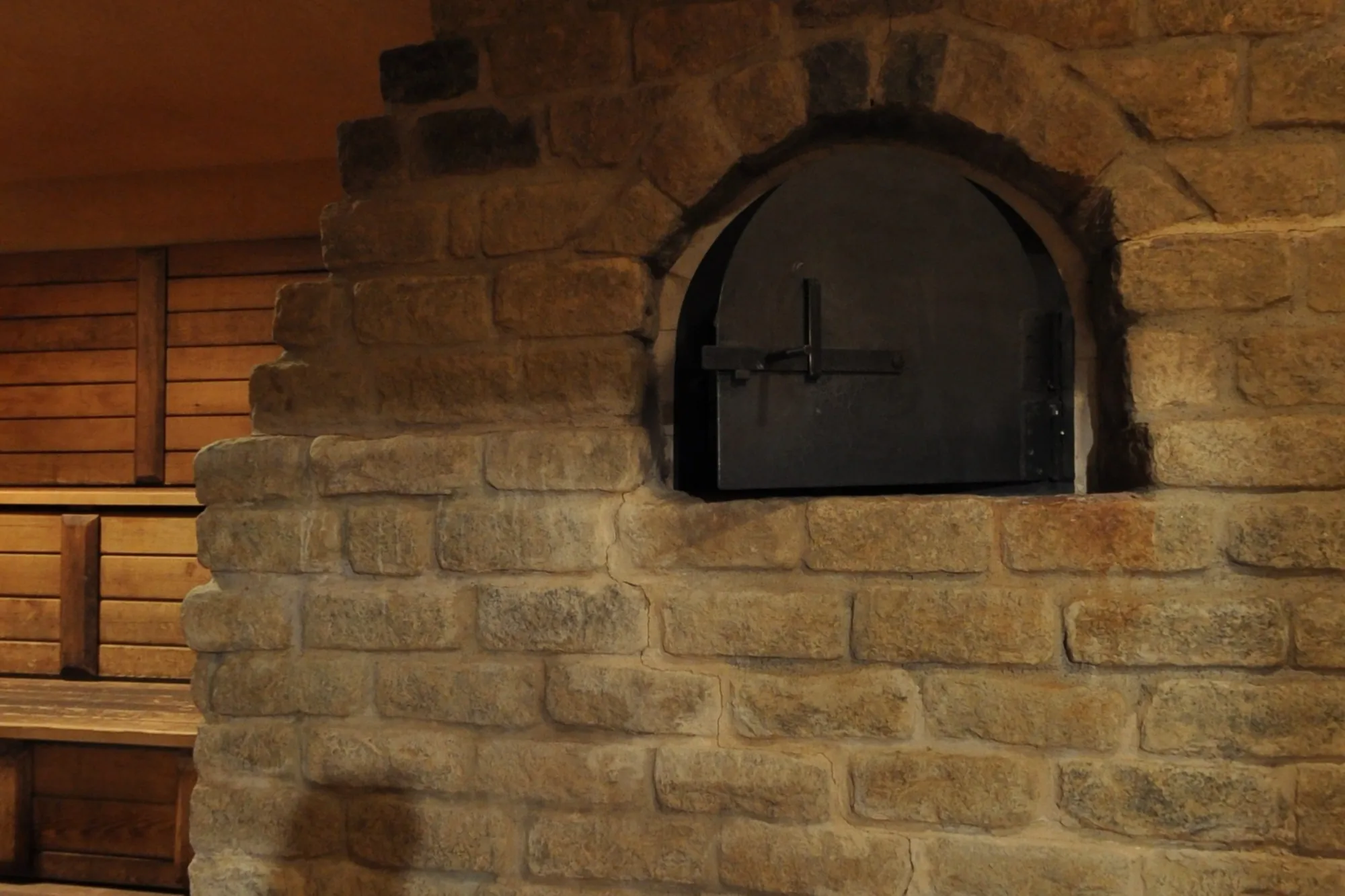 The stone stove of the dry sauna, its cast iron door shut.