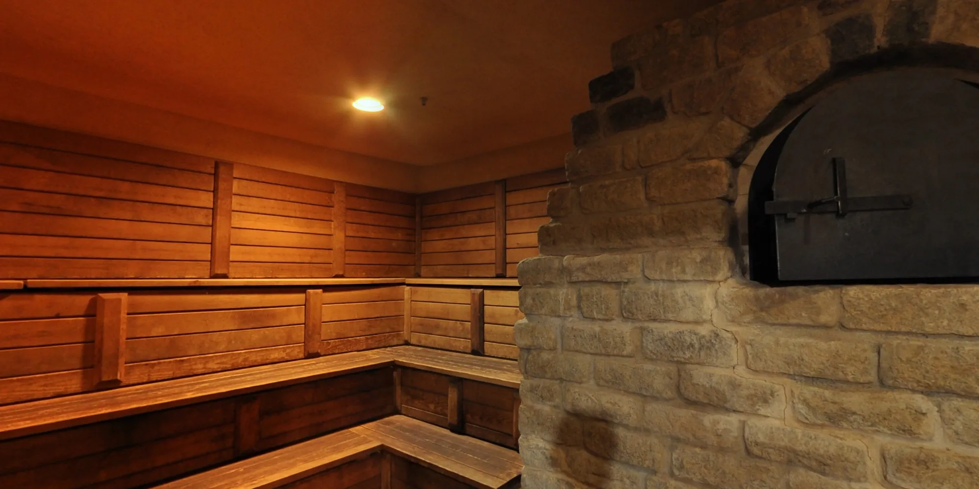 The dry sauna: tiered cedar benches meeting the stone stove.