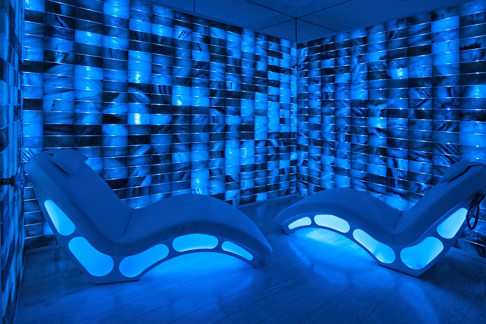 The same room lit deep blue, two loungers glowing.