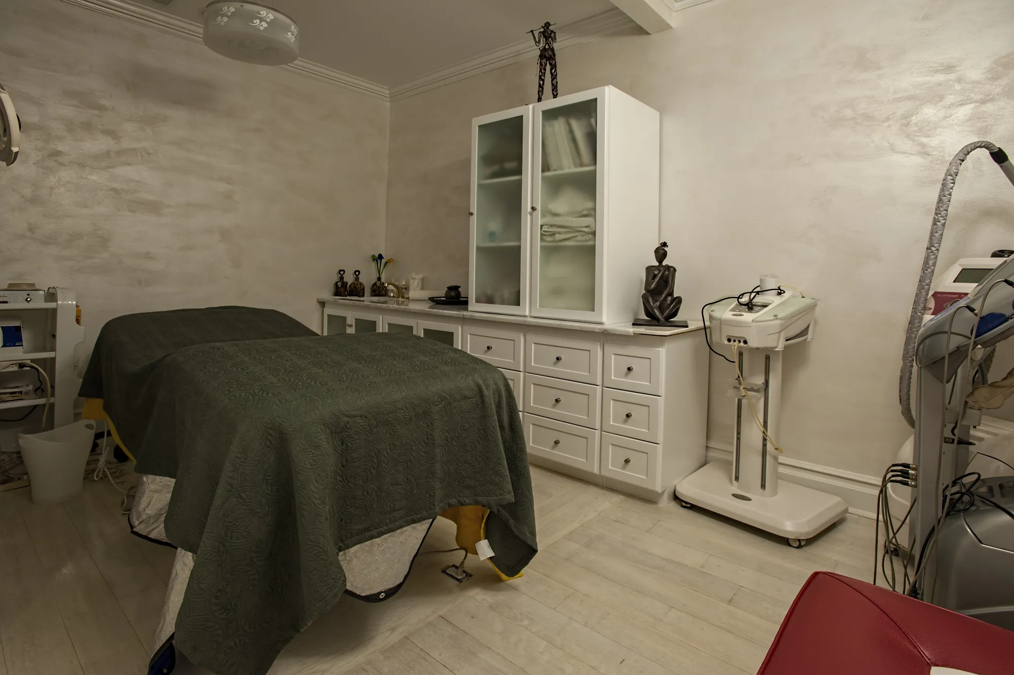 A treatment room at BRC: a made-up massage table, a glass shower and white cabinetry.