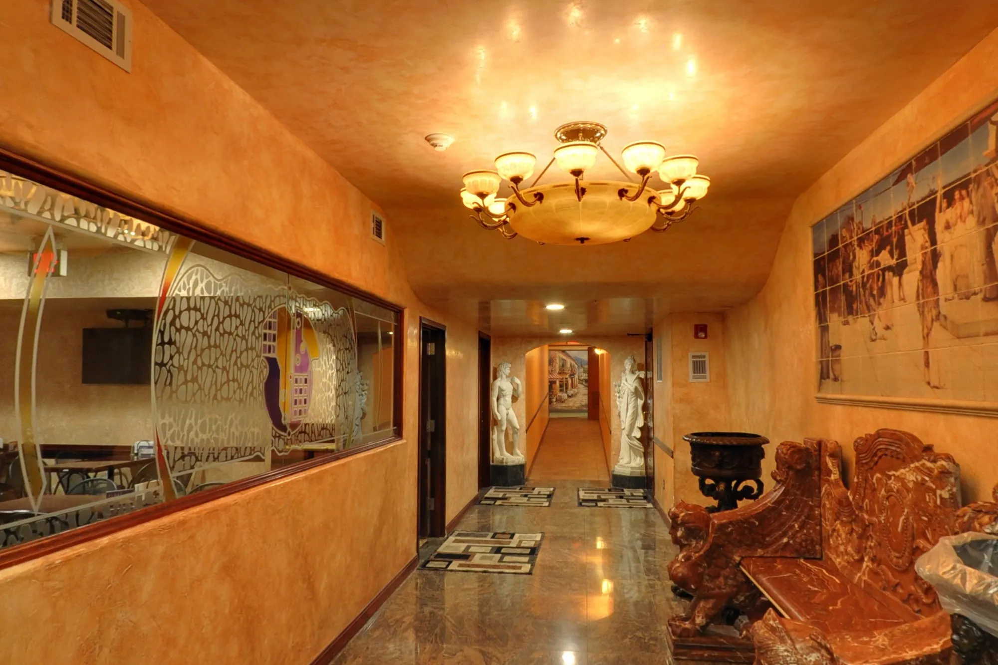 BRC's lobby corridor: marble floor, the tiled mural, carved wooden benches and statues down the hall.