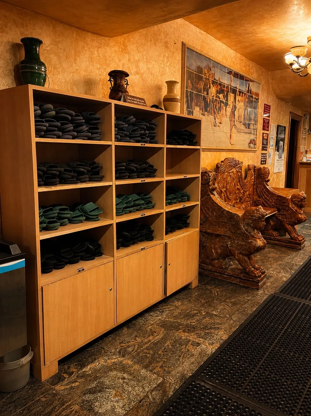 Shelves of spa slippers by a carved bench.