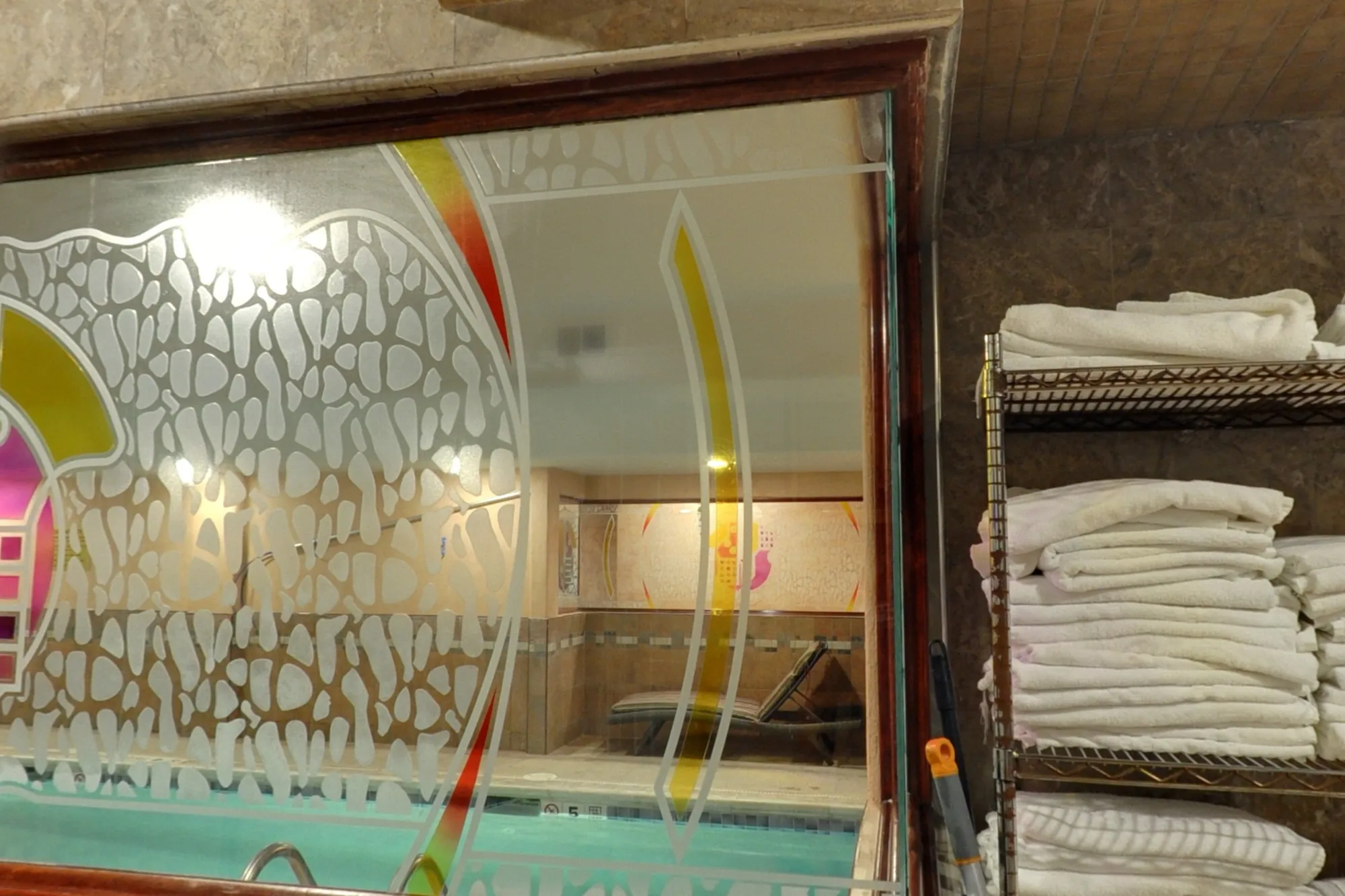 Fresh towels stacked by the etched window into the pool room.